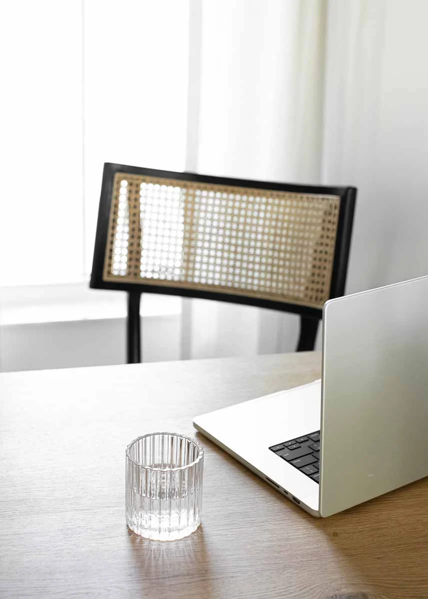 Open silver laptop on table beside glass of water