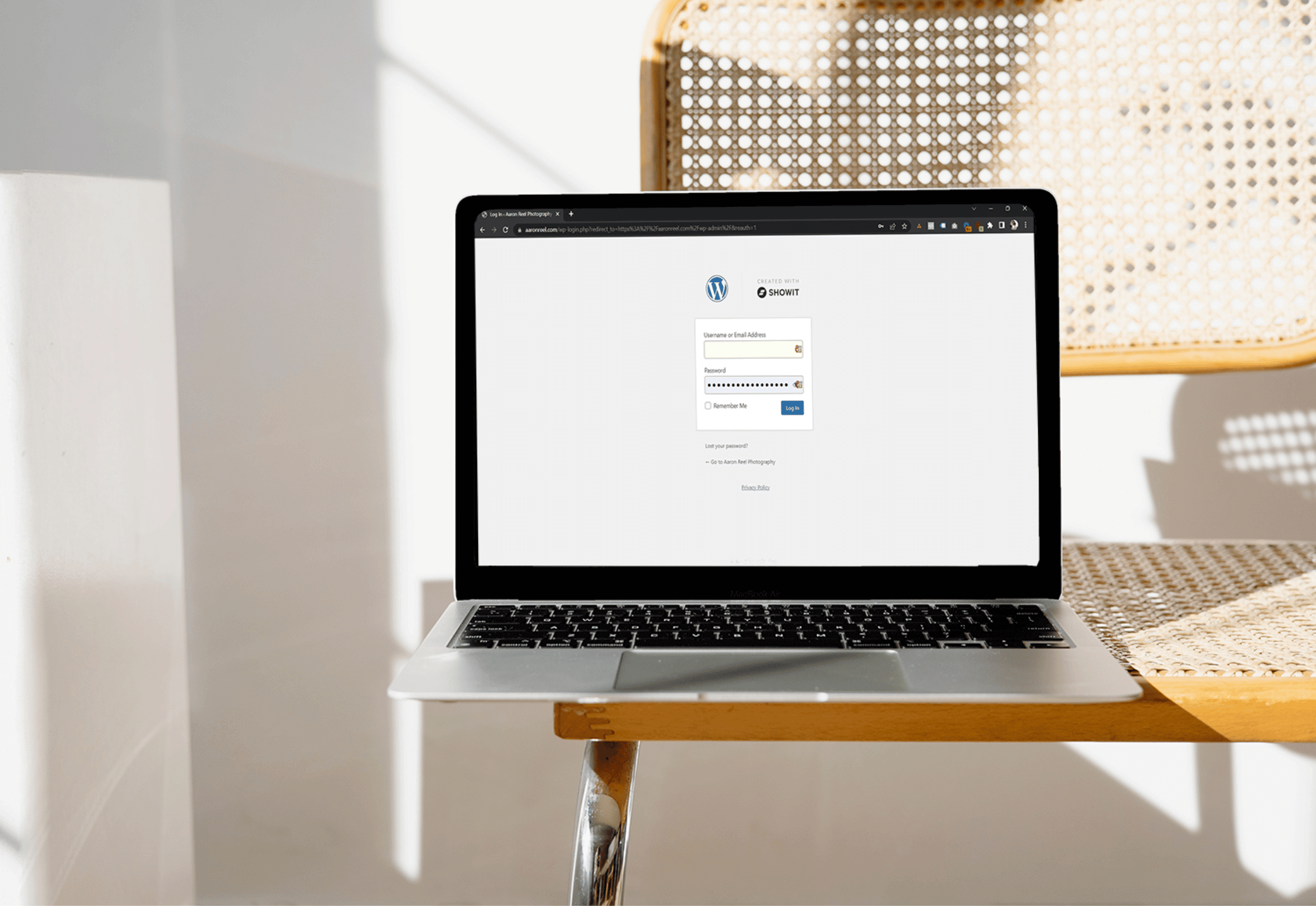 Laptop on a rattan chair displaying a wordpress login page with showit branding