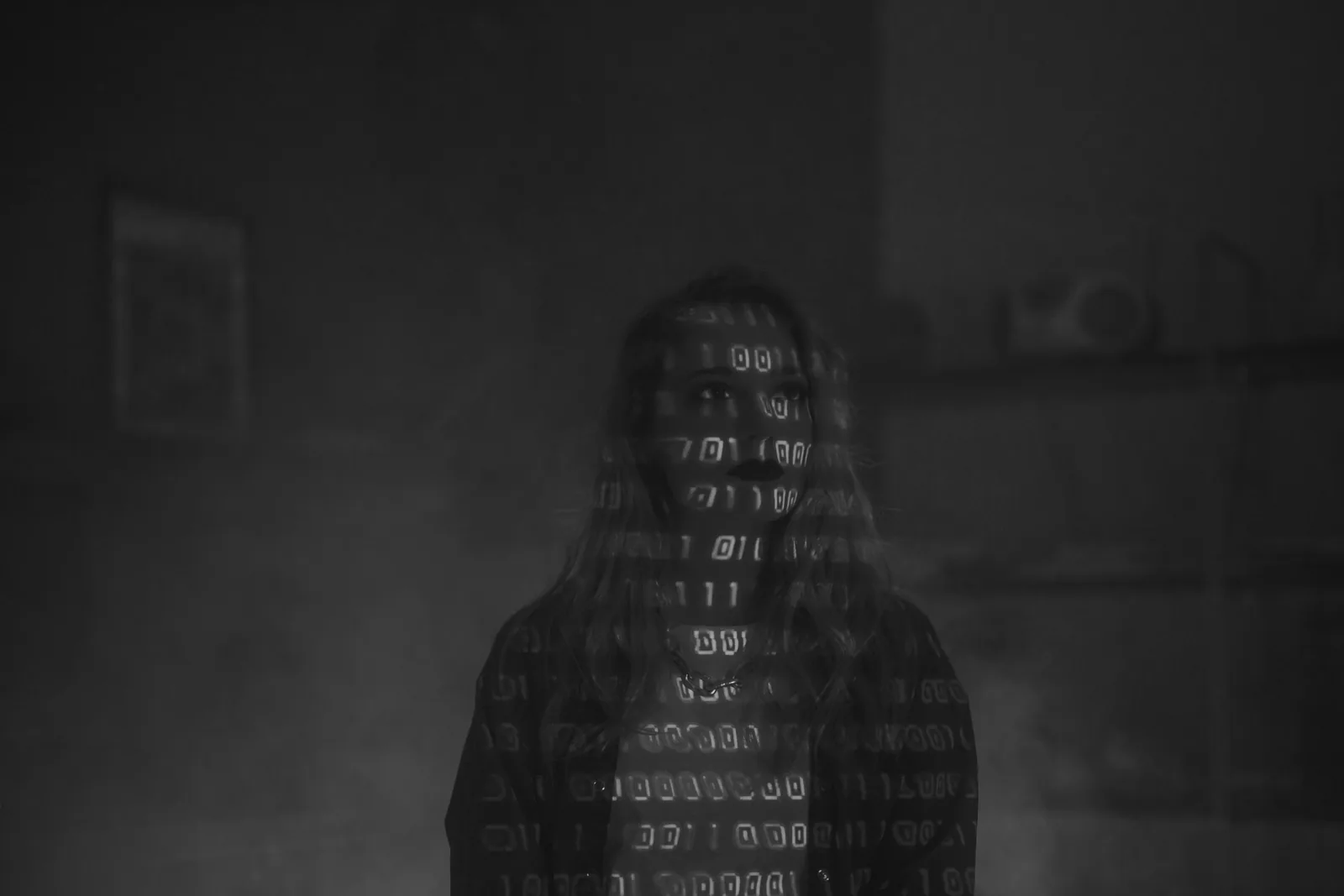 Black and white photo of a woman with lines of binary code projected across her face and hair
