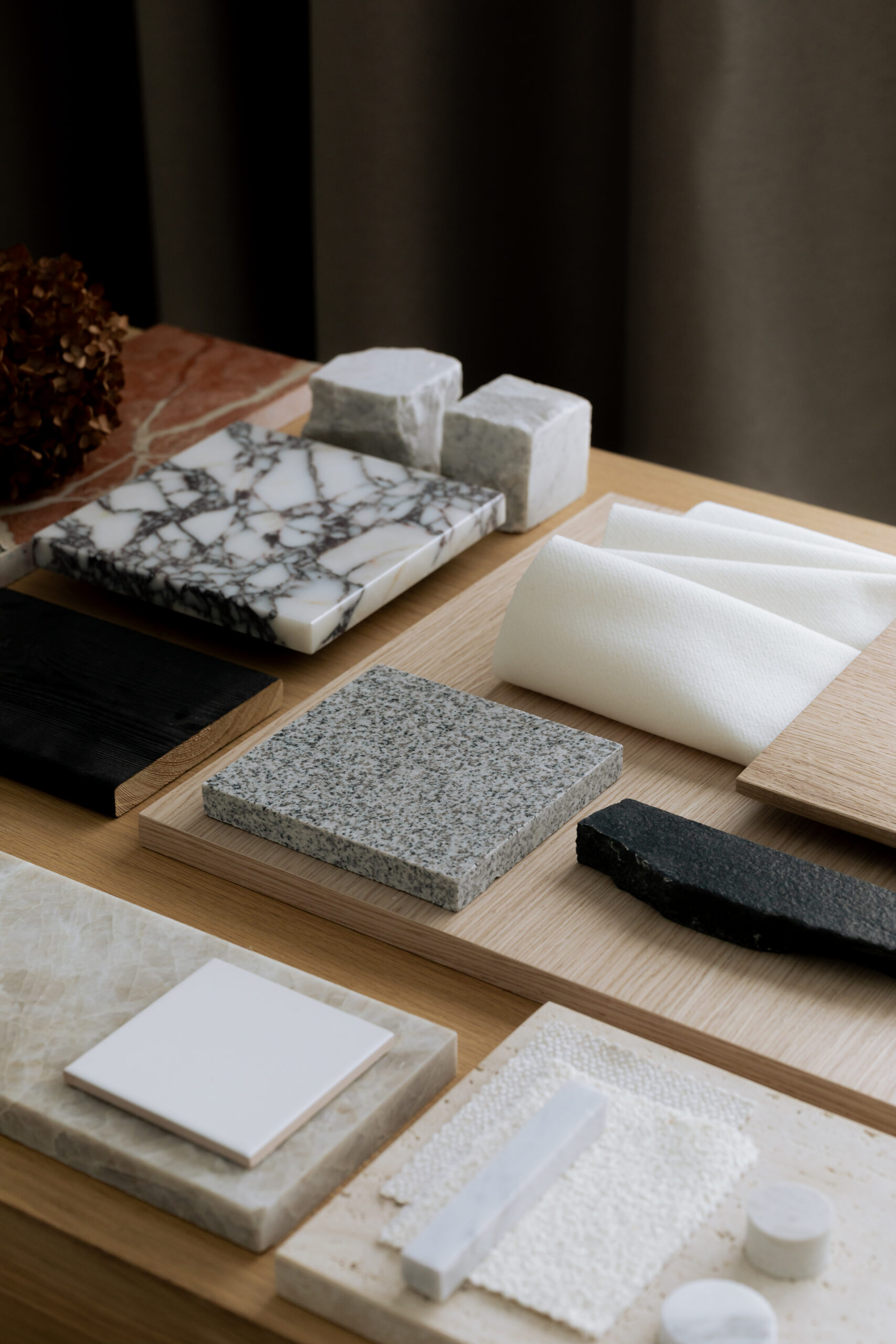 Assorted material samples including marble, granite, stone, wood, and fabric swatches arranged on a table