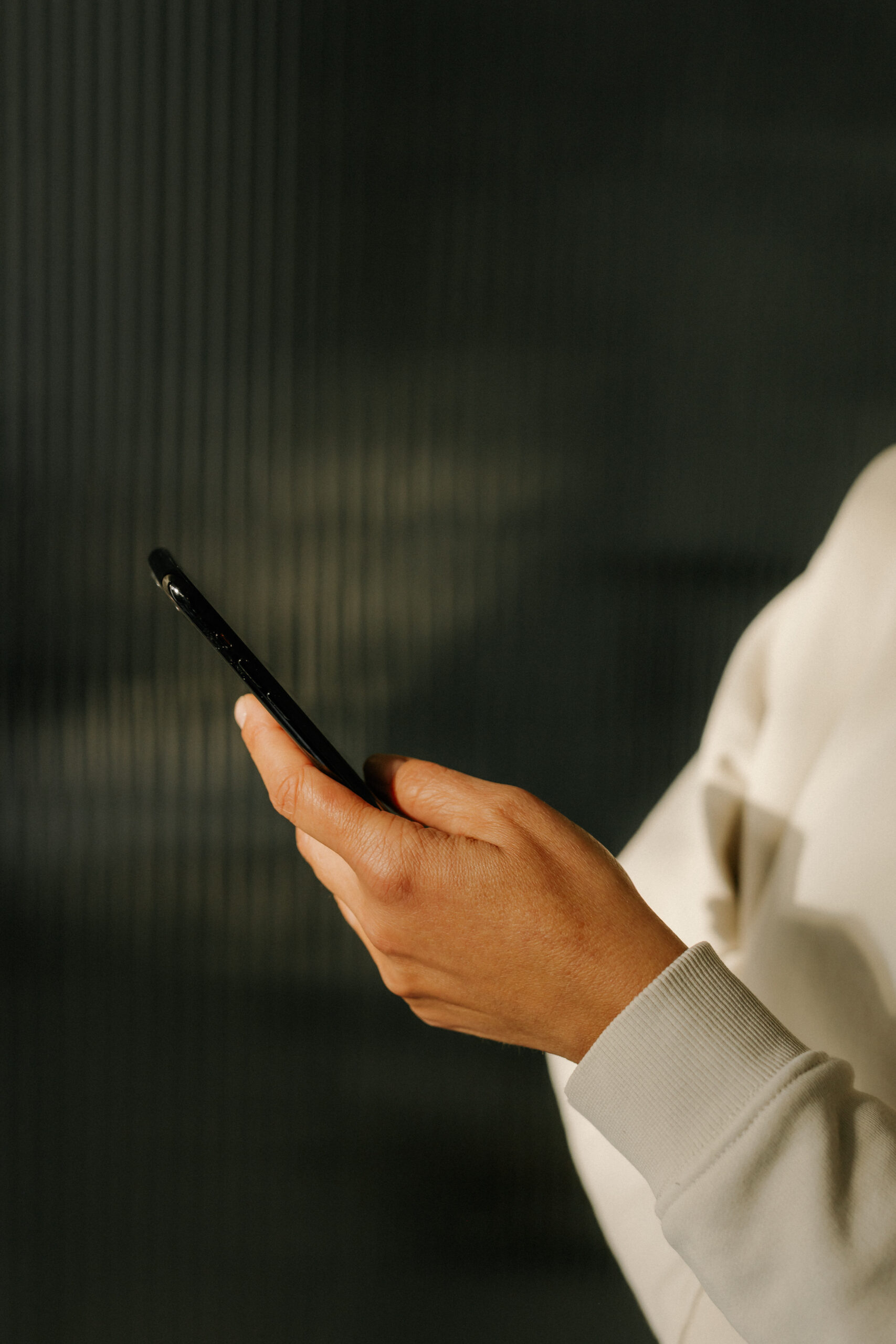Close-up of a hand holding a smartphone against a dark background
