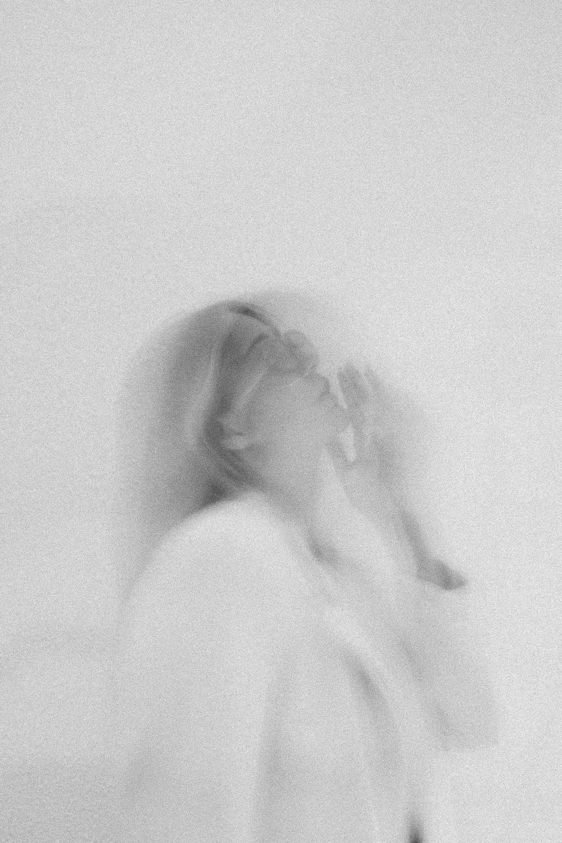 Black and white motion blur portrait of a woman in a white blazer turning toward the light